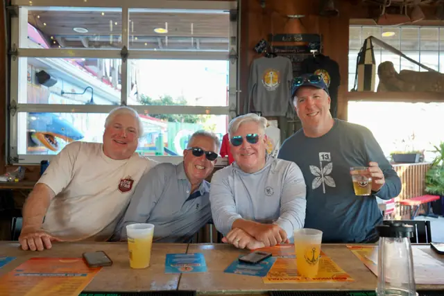 Four friends at the bar with beers and crushes