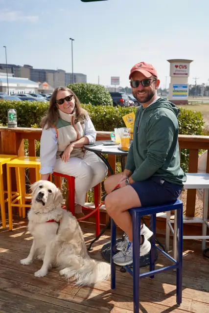 A couple and their golden retriever on the sunny deck