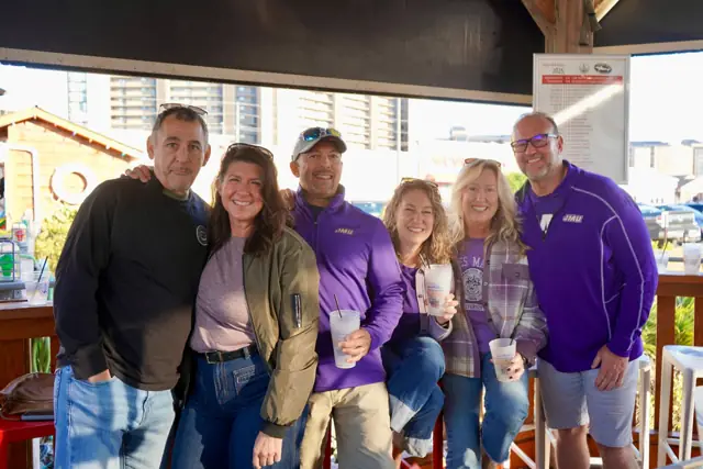 A group of friends in game-day purple at the outdoor bar