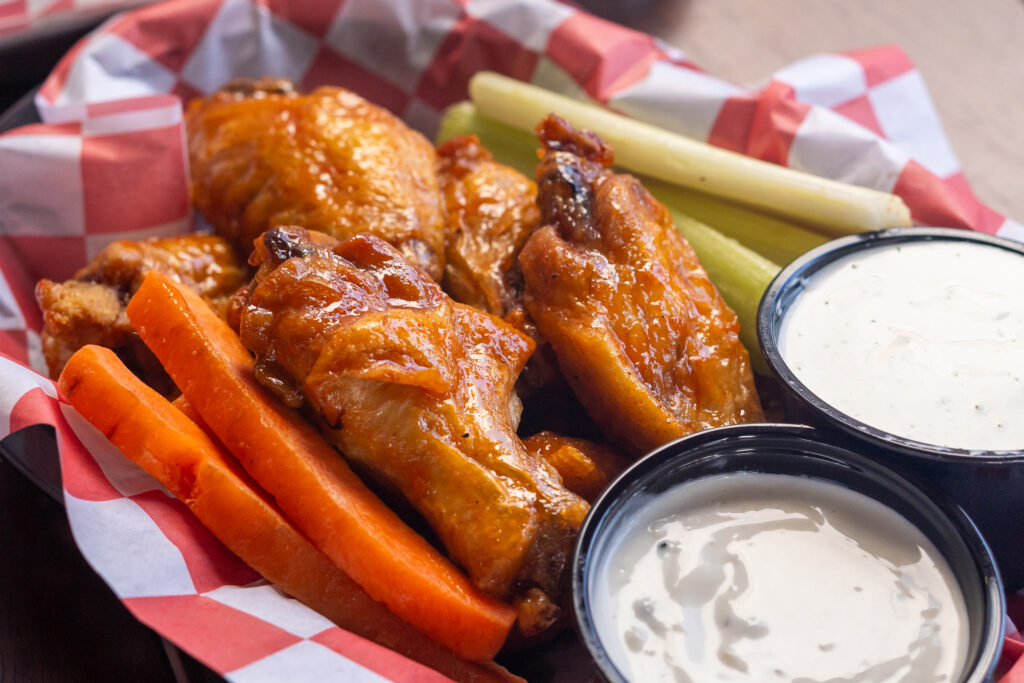 chicken wings, carrots, celery and dips on a plate